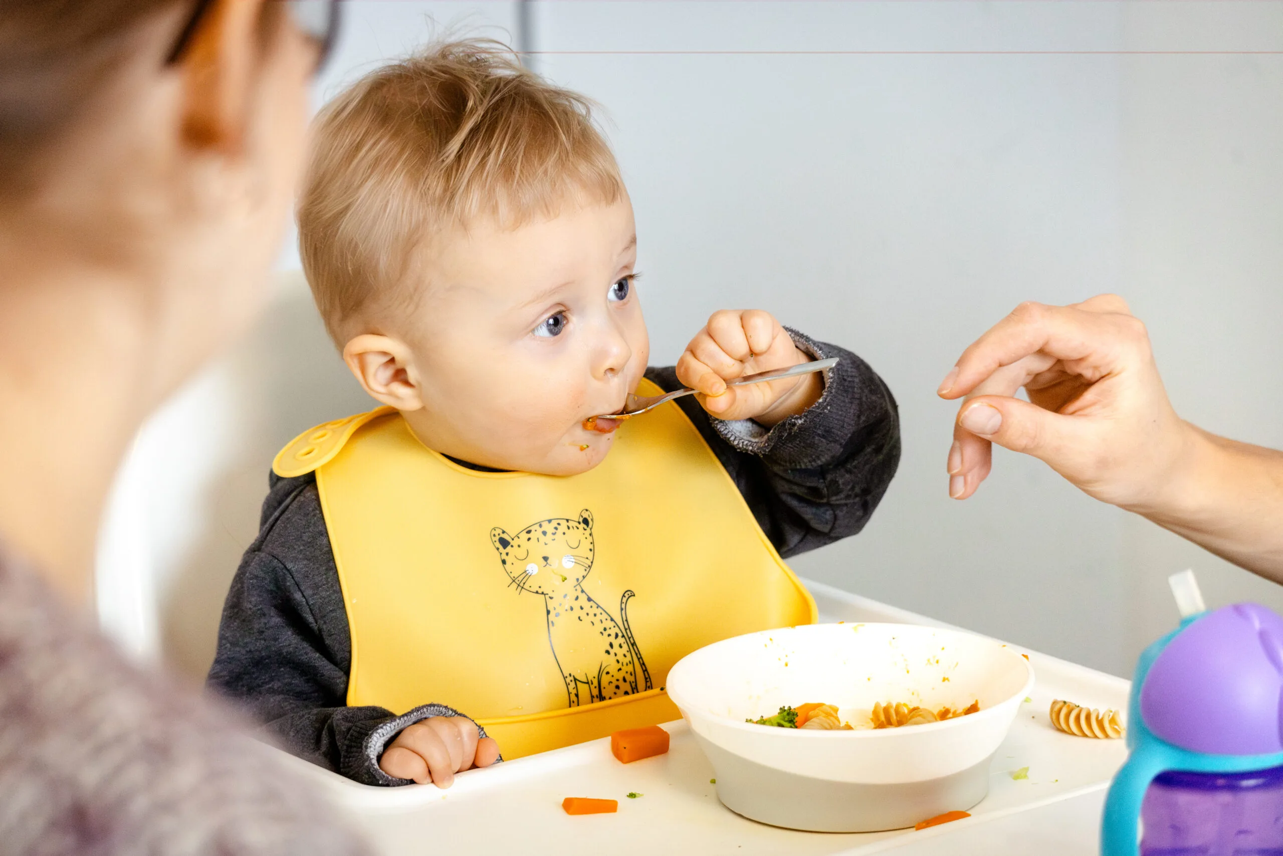 Pieni lapsi syö ruokaa lusikalla.